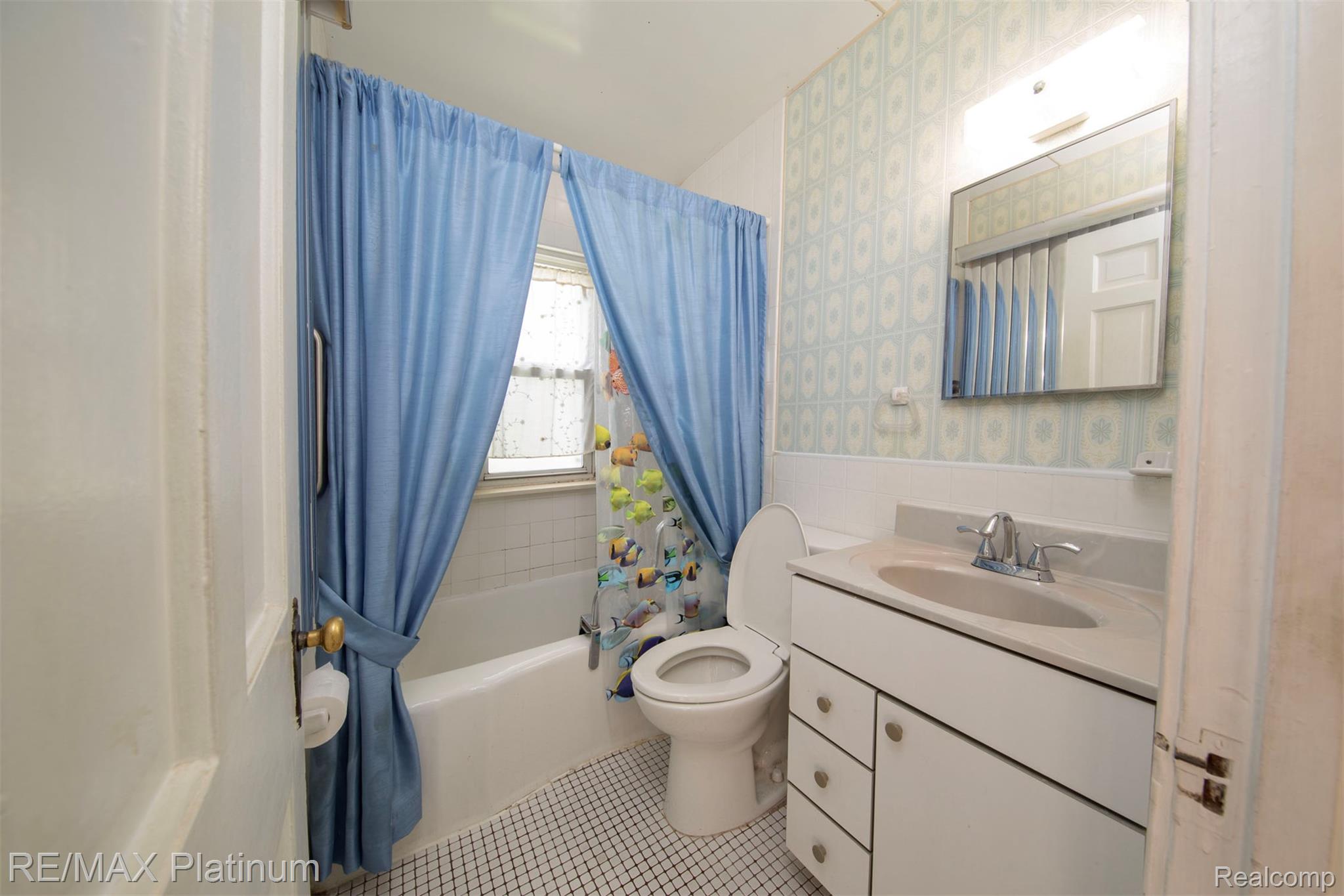18696 Inkster Road Redford, MI 48240 - Photo 10 of 14 Bathroom featuring white hexagonal tile flooring, a built-in bathtub with white subway tile surround, a window with frosted glass, and a vanity with an integrated sink