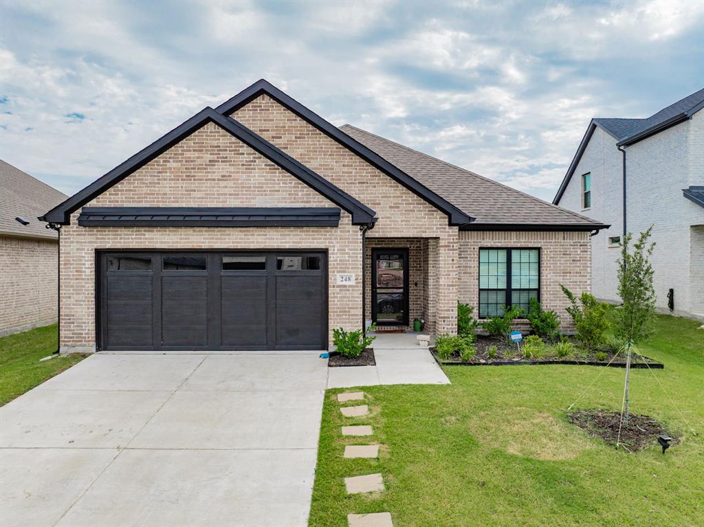 View of front of property with a garage, a front lawn, driveway, and brick siding