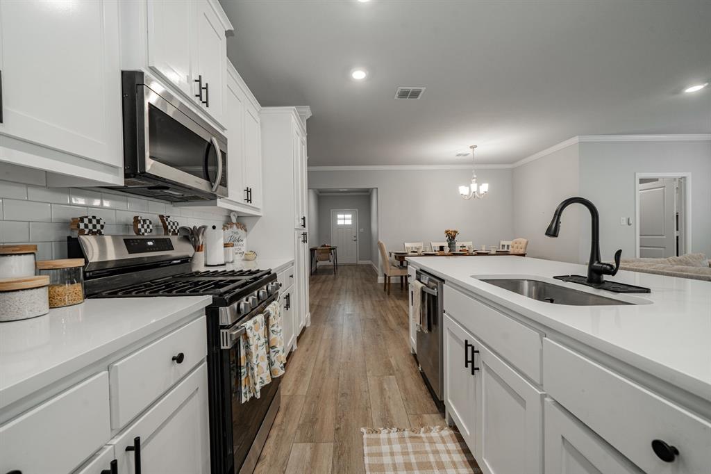 248 Waters Rdg Drive Lavon, TX 75166 - Photo 10 of 36 Kitchen with stainless steel appliances, white cabinetry, light wood-style flooring, ornamental molding, and suspended lighting