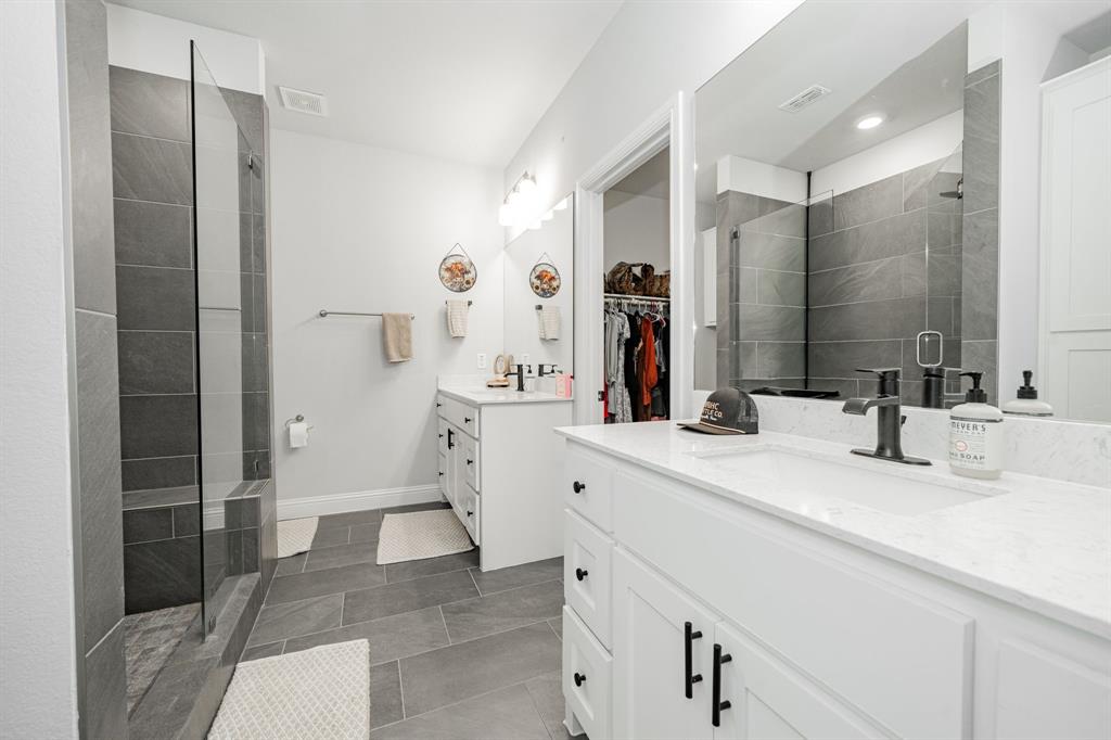 248 Waters Rdg Drive Lavon, TX 75166 - Photo 23 of 36 Bathroom featuring a stall shower, a spacious closet, two vanities, and dark tile patterned flooring
