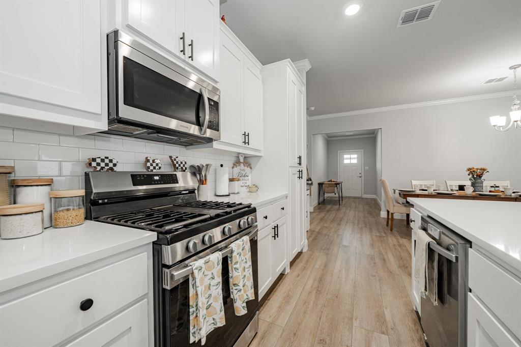 248 Waters Rdg Drive Lavon, TX 75166 - Photo 8 of 36 Kitchen with stainless steel appliances, white cabinetry, crown molding, light wood finished floors, and suspended lighting