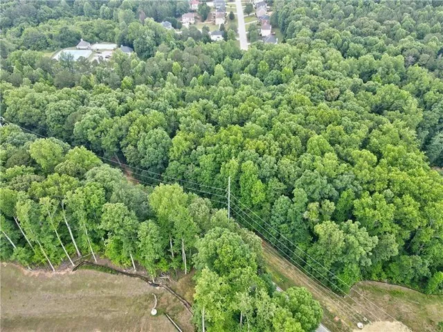an aerial view of a house with a lush green forest
