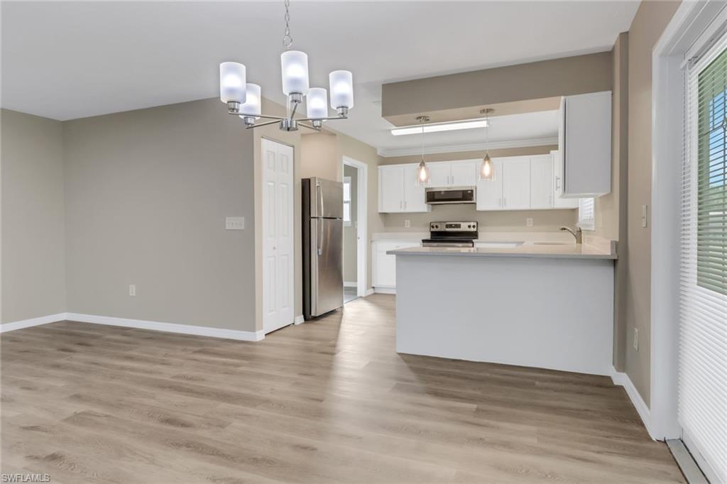 4599 Mongite Road North Port, FL 34287 - Photo 8 of 28 a kitchen with stainless steel appliances granite countertop a refrigerator a sink dishwasher a stove and a dining table with wooden floor