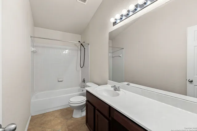 a bathroom with a granite countertop sink a toilet a shower and a mirror