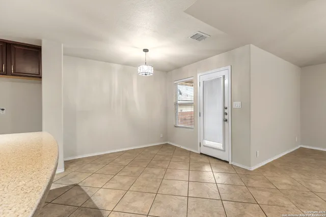an empty room with kitchen view and natural light
