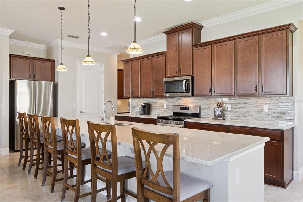2665 Meadowedge Loop St. Cloud, FL 34772 - Photo 10 of 53 a kitchen with stainless steel appliances granite countertop a stove a sink a microwave a refrigerator with a dining table and chairs