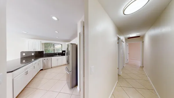 a large white kitchen with a refrigerator and a sink