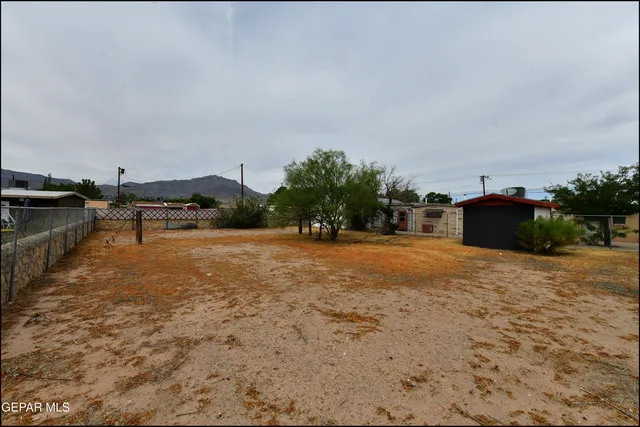 a view of a dry yard with wooden fence