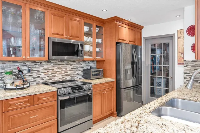 a kitchen with granite countertop wooden cabinets stainless steel appliances and a counter space