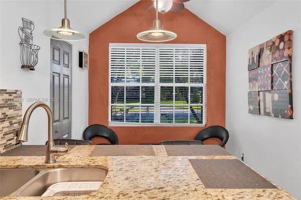 a view of a kitchen with granite countertop a dining table chairs and a large window