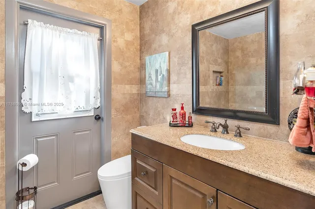 a bathroom with a granite countertop sink toilet and large mirror