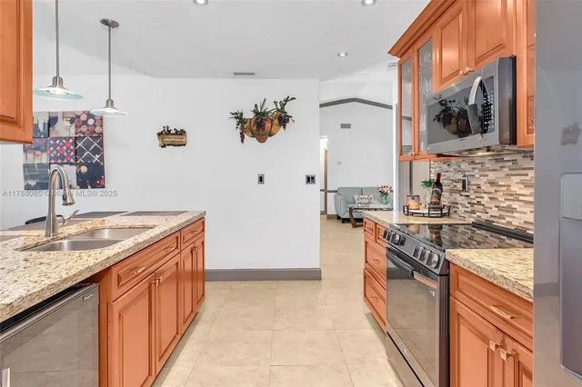 a kitchen with stainless steel appliances granite countertop a sink and a refrigerator