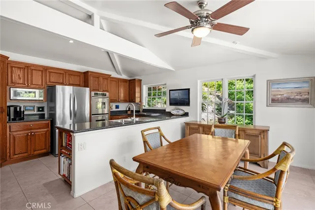 a kitchen with stainless steel appliances granite countertop a stove a refrigerator a kitchen island a table and chairs with a large window