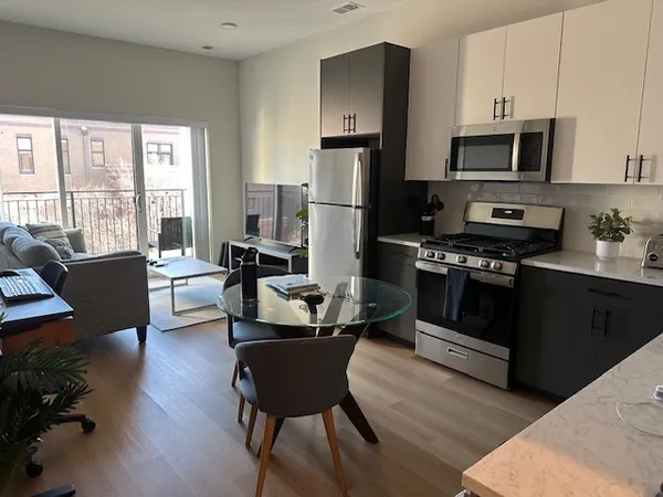 a kitchen with stainless steel appliances a stove a sink refrigerator and a dining table