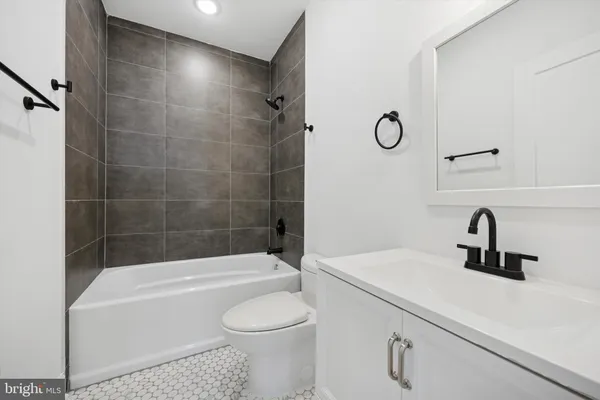 a bathroom with a sink a toilet a mirror a bathtub and shower