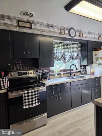 a kitchen with stainless steel appliances granite countertop a refrigerator a sink dishwasher a stove and a dining table with wooden floor