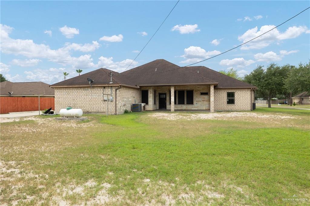 401 Ric Mar Street Edinburg, TX 78541 - Photo 16 of 18 Rear exterior featuring a covered patio, brick and stone facade, dark shingle roof, and ample green space