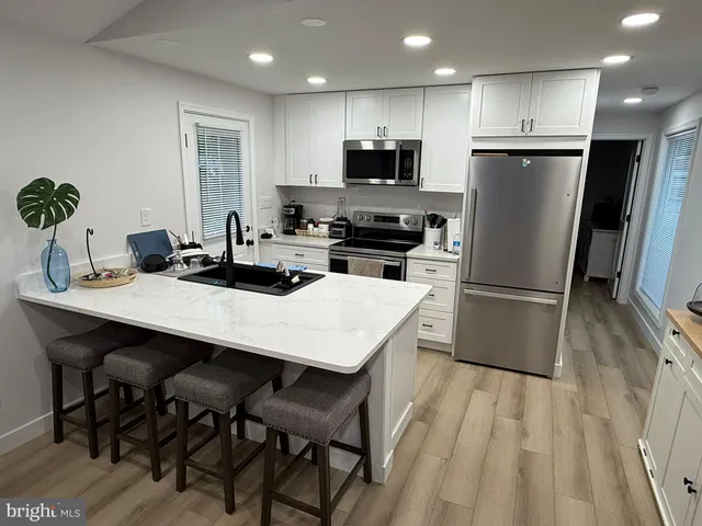 a kitchen with stainless steel appliances a dining table chairs refrigerator and microwave