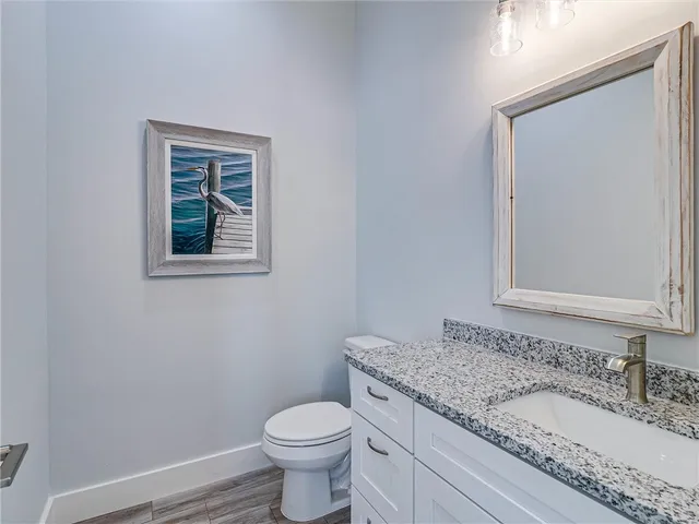 a bathroom with a granite countertop toilet a sink and mirror