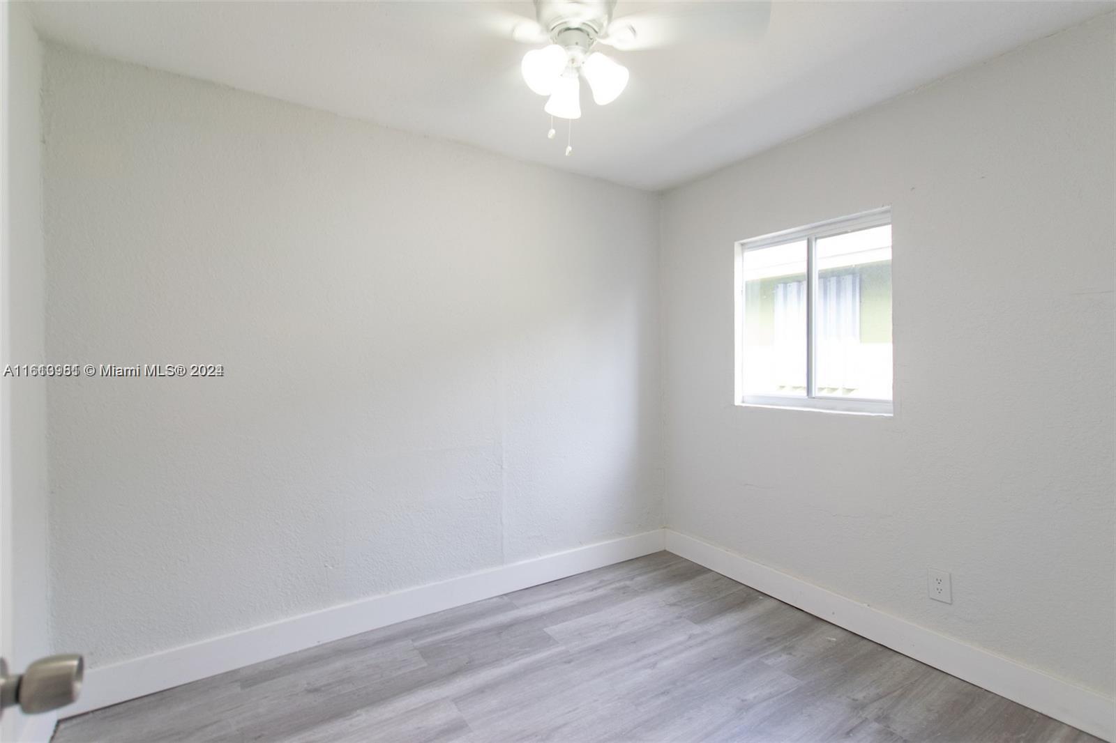1113 Northwest 103rd Street, Unit 1 Miami, FL 33150 - Photo 11 of 12 wooden floor in an empty room with a window
