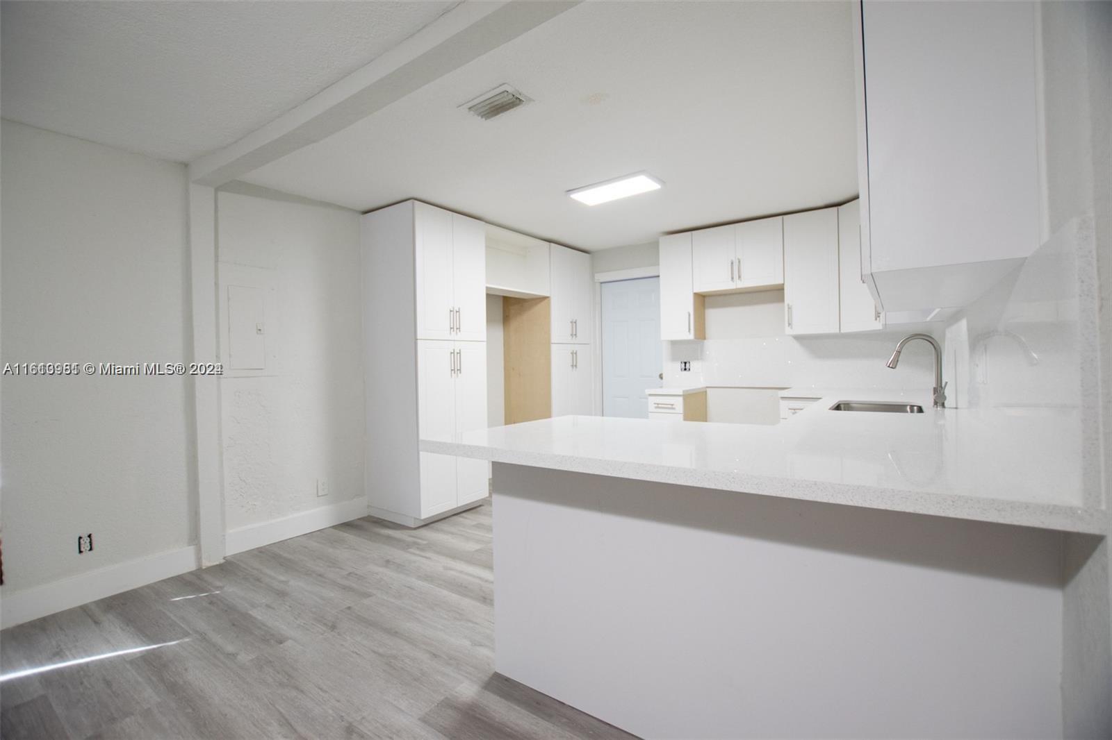 1113 Northwest 103rd Street, Unit 1 Miami, FL 33150 - Photo 5 of 12 a kitchen with granite countertop white cabinets and refrigerator