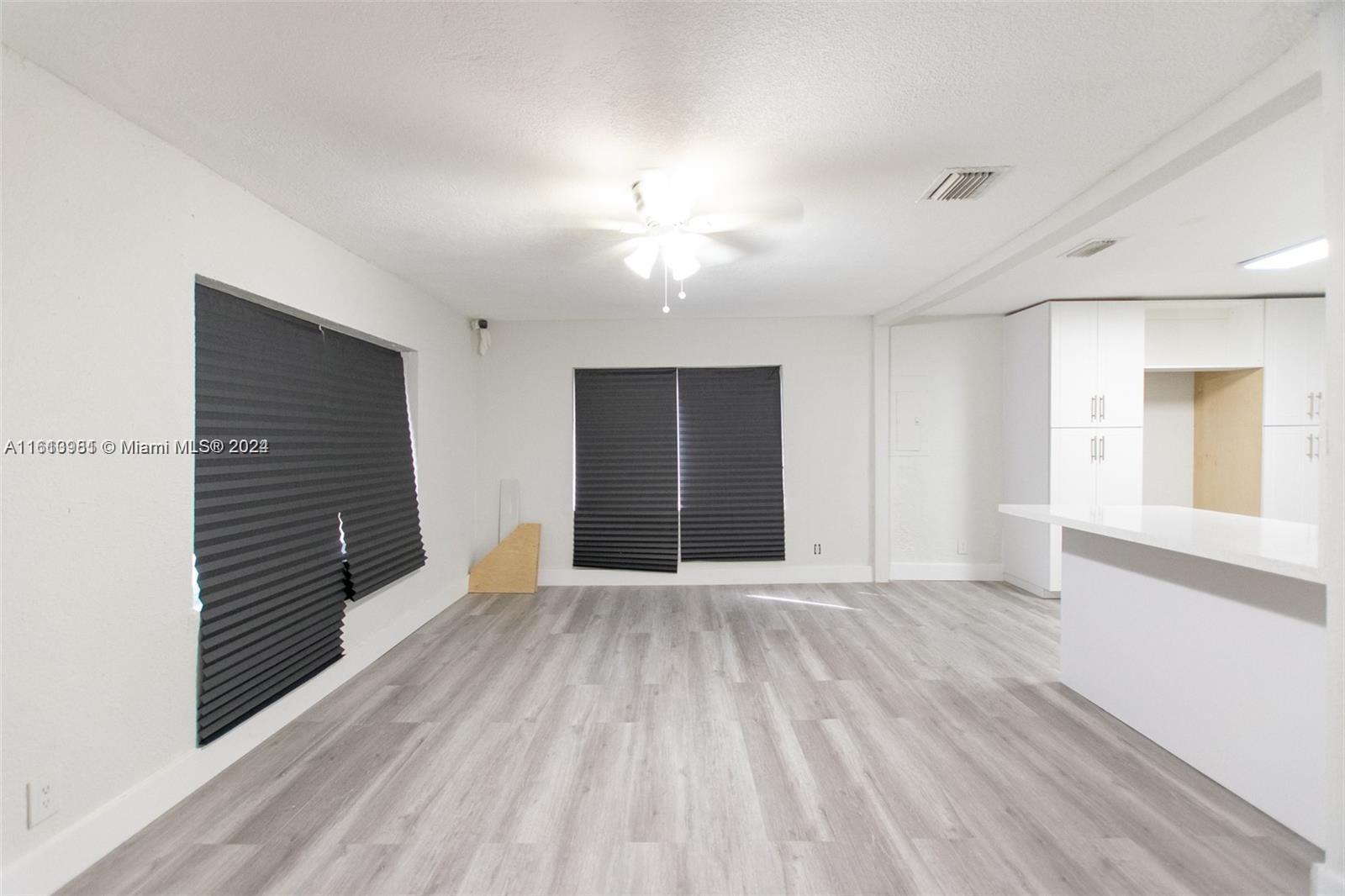 1113 Northwest 103rd Street, Unit 1 Miami, FL 33150 - Photo 6 of 12 a view of an empty room with wooden floor and a window