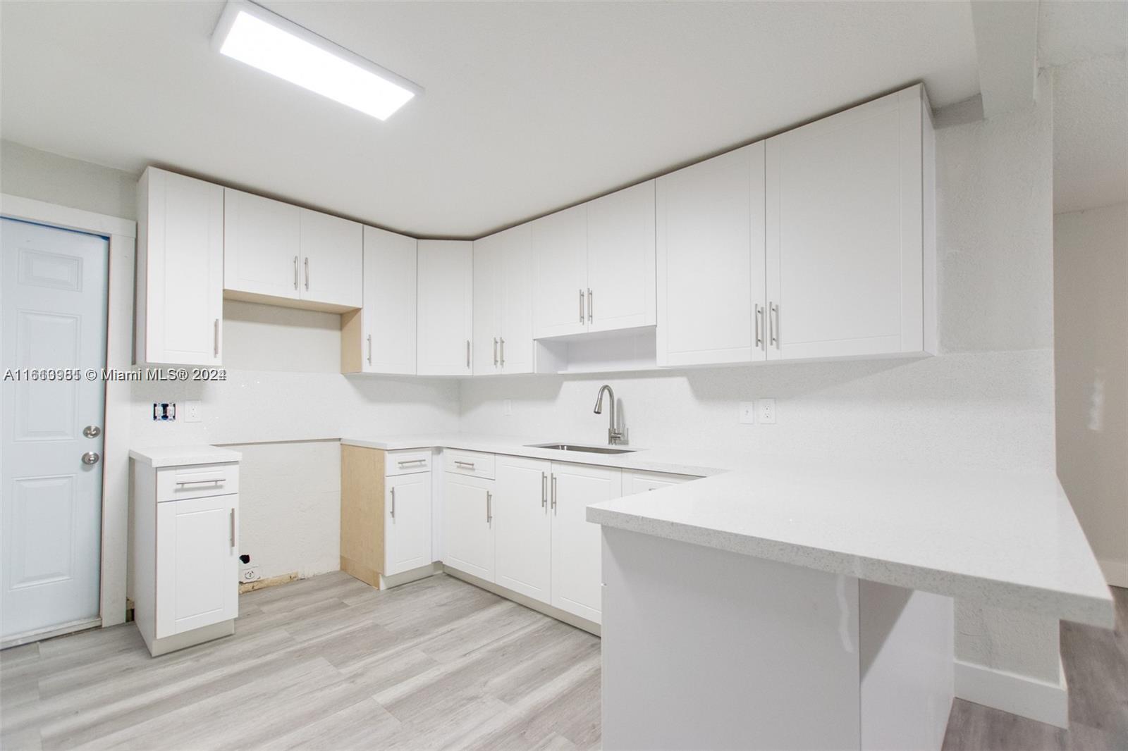 1113 Northwest 103rd Street, Unit 1 Miami, FL 33150 - Photo 8 of 12 a kitchen with granite countertop white cabinets and white appliances