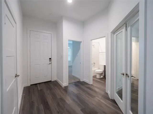a view of a hallway with wooden floor and a bathroom