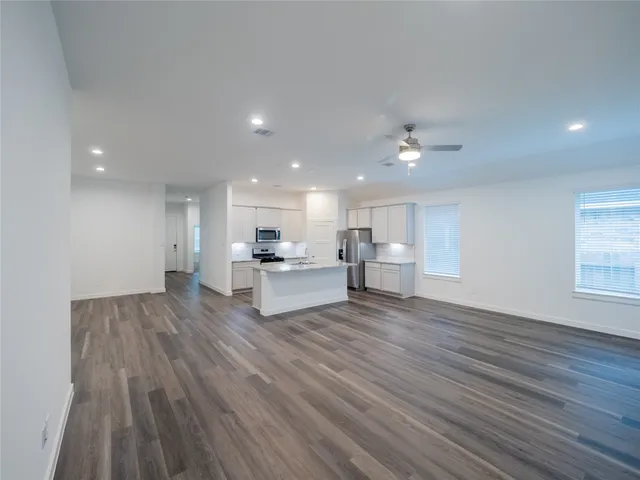a view of kitchen with kitchen island wooden floors and stainless steel appliances
