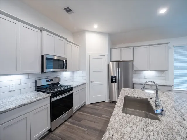 a kitchen with granite countertop stainless steel appliances a stove a sink and a refrigerator