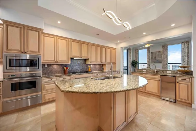 a large kitchen with kitchen island granite countertop a stove top oven a sink a counter space and cabinets