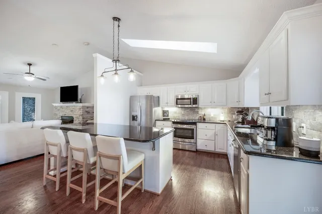 a kitchen with stainless steel appliances kitchen island granite countertop a wooden floor and white cabinets