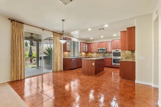 a kitchen with stainless steel appliances kitchen island granite countertop a refrigerator a stove top oven and a sink with wooden floor