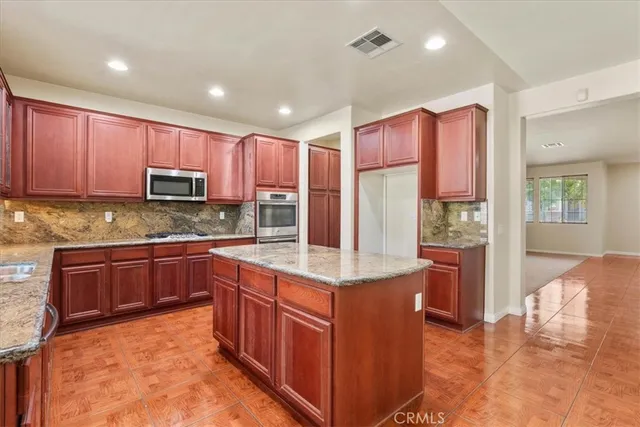 a kitchen with stainless steel appliances granite countertop wooden cabinets a stove a sink and a large refrigerator