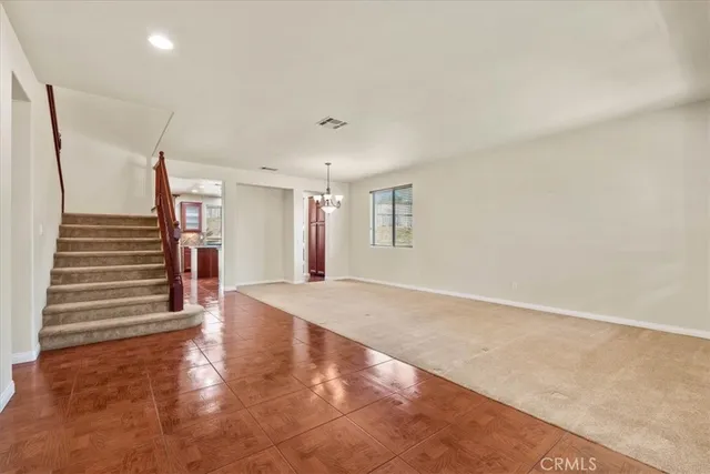 a view of an empty room with wooden floor and stairs