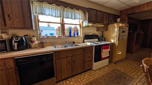 a kitchen with stainless steel appliances granite countertop a refrigerator a sink a stove a counter space and cabinets