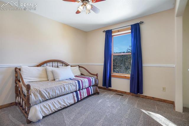 405 Cochetopa Road Florissant, CO 80816 - Photo 16 of 28 Bedroom 1 on the main level with newer carpet (1 year old), ceiling fan, wall-to-wall closet, 3.5 hand stained baseboards and hand stained solid door for noise reduction and views!