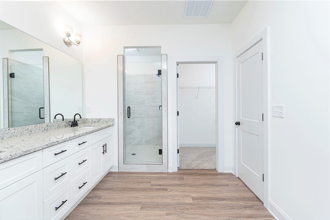 328 Point Road Westminster, SC 29693 - Photo 18 of 37 This primary bathroom offers a dual vanity, sleek shower, and a convenient walk-in closet.