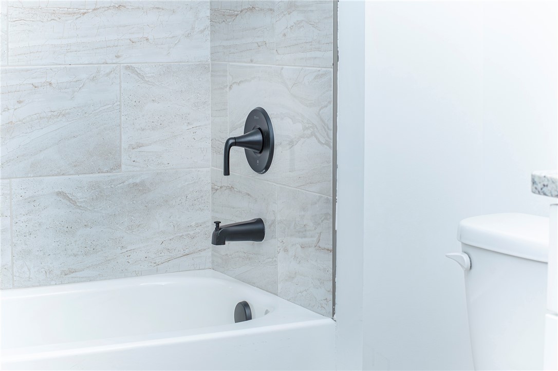 328 Point Road Westminster, SC 29693 - Photo 28 of 37 This bathroom features sleek black fixtures complementing the elegant tiled shower surround and a clean bathtub.