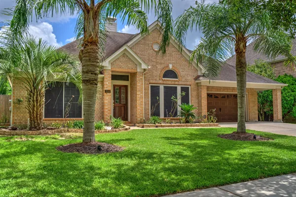 a front view of a house with a garden and trees