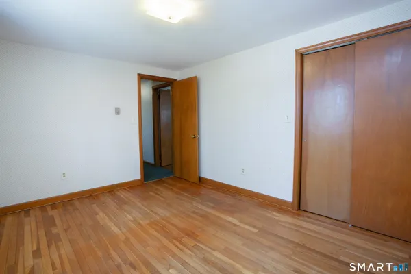 a view of an empty room with wooden floor and closet