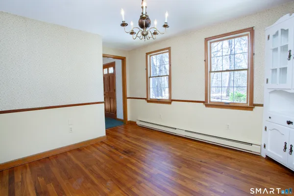 an empty room with wooden floor chandelier and windows