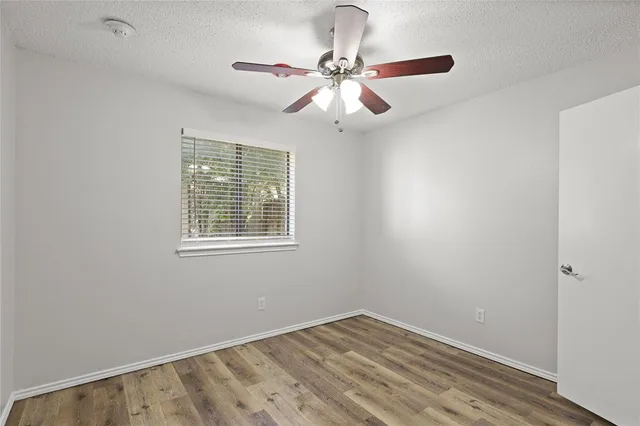 an empty room with a window and a fan