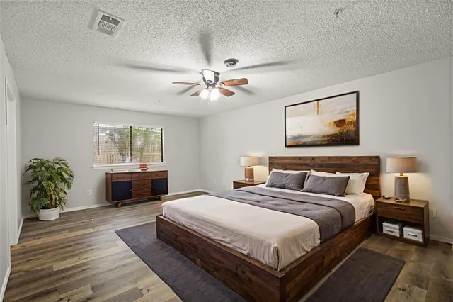 a spacious bedroom with a bed a dresser and potted plants