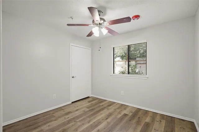 an empty room with a window and a fan