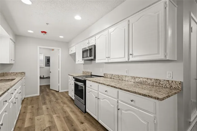 a kitchen with granite countertop white cabinets and stainless steel appliances