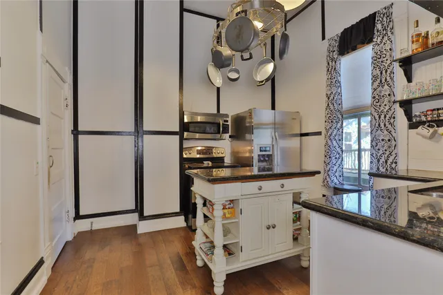 a kitchen with stainless steel appliances granite countertop a refrigerator a stove and a wooden floors