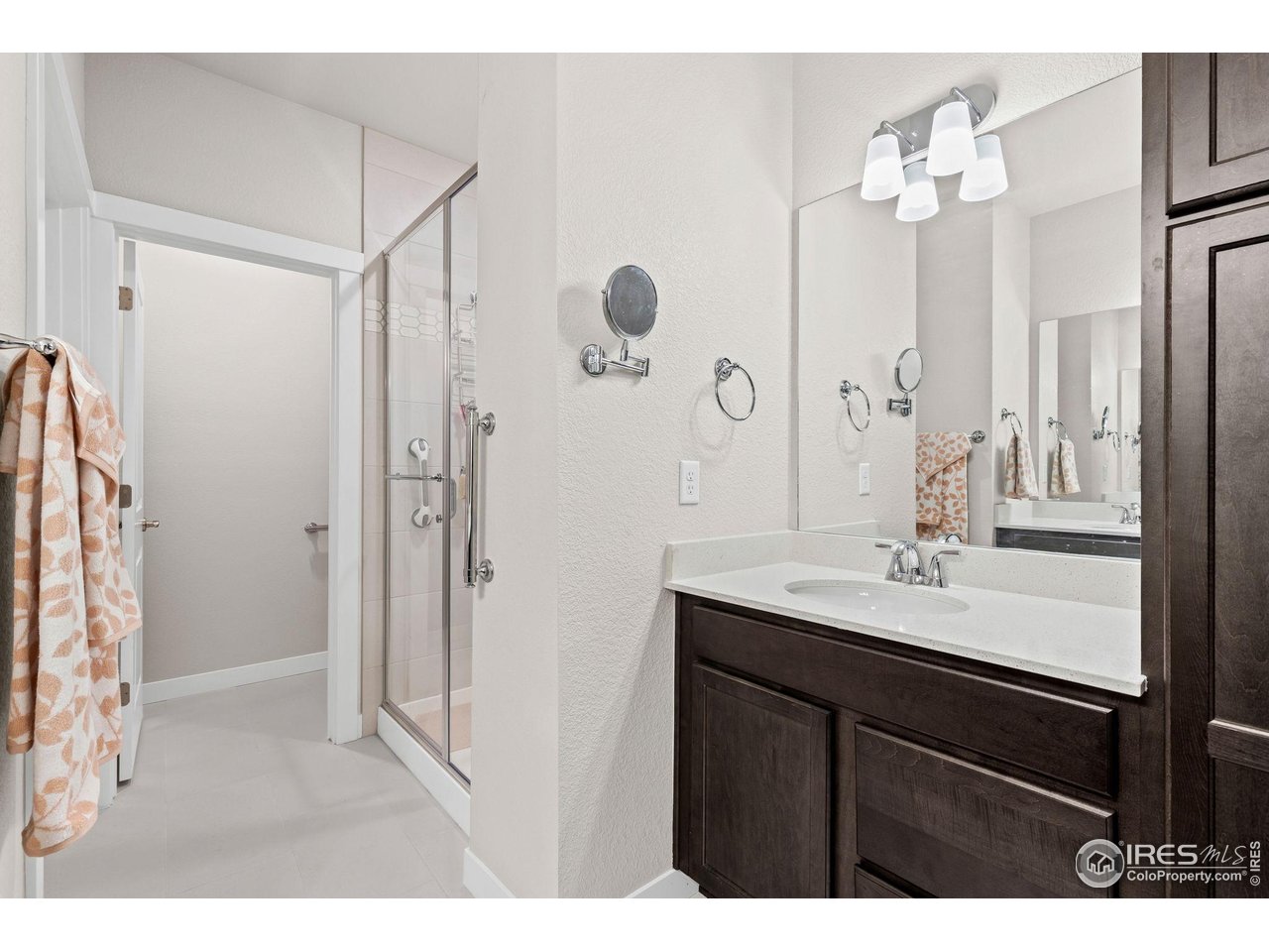 330 High Point Drive, Unit B103 Longmont, CO 80504 - Photo 14 of 18 a bathroom with a sink a mirror a vanity and a shower