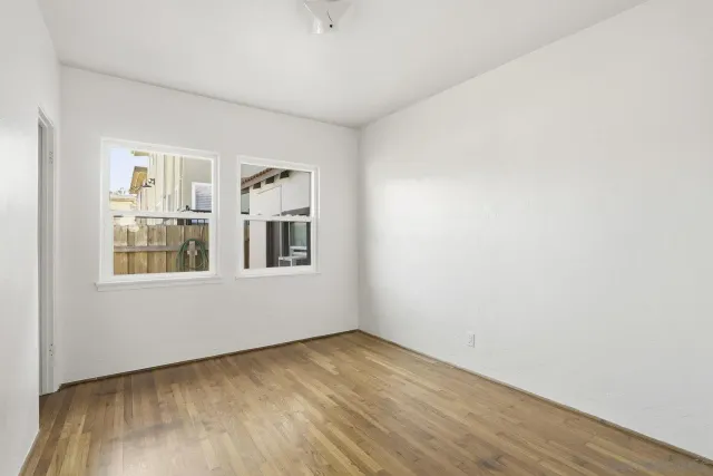 a view of an empty room with window and wooden floor