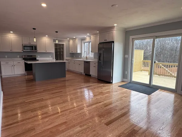 a large kitchen with stainless steel appliances kitchen island granite countertop a refrigerator a sink dishwasher a stove and a large countertops with wooden floor